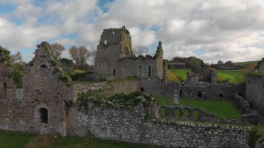 Canlı sonbahar renkleriyle çevrili, yemyeşil bir şatonun güzelliğini keşfedin. Perili harabeler dramatik bulutların arka planına karşı dimdik ayakta duruyor..