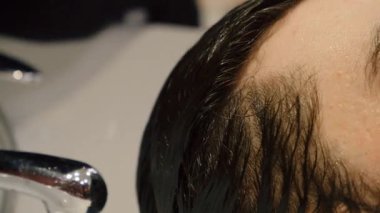 Bir müşteriye berber saçlarını suyla durulama görüntüsü.
