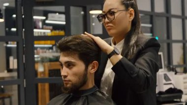 Profesyonel saç stilisti müşterisi üzerinde titizlikle çalışıyor..