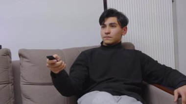 Oturma odasında dinlenen ve evde kanal değiştiren adam..