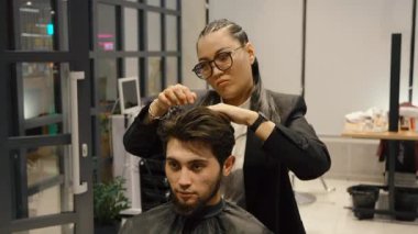 Müşteri için modern bir saç kesimi yaratmak için makas kullanan erkek stilisti.