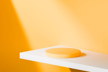 Dairesel turuncu platform köşegen gölgeli parlak bir stüdyoda asılı..