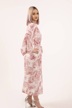 Beyaz arka planda desenli gece elbisesi içinde zarif bir kadın modeli..