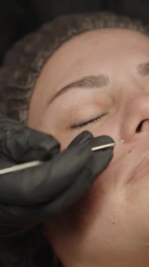 Güzellik salonunda burun ve yüz bakımı yapan kadınların gözeneklerini temizlemek için metal aletler kullanan kozmetik uzmanını kapatın..