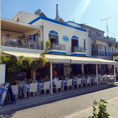 Kos, Yunanistan - 17 Eylül 2019: Şehrin ortasındaki tipik küçük Yunan atmosferik restoranları. Dışarıda renkli sandalyeler ve masalar.