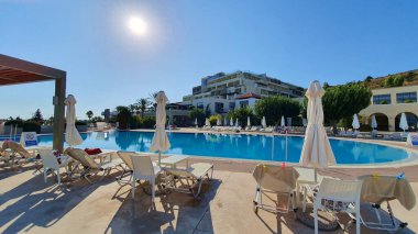 Kos, Yunanistan - 15 Eylül 2019: Salgının etkileri. Güneşli bir günde palmiye ağaçlarının altında boş güneşlenirler ve yüzme havuzları.