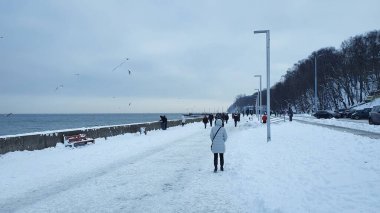 Gdynia, Polonya - 17 Ocak 2021: kış yürüyüşü. Polonya 'nın Gdynia kentindeki Baltık deniz bulvarında yürüyen insanlar. Gdynia, Polonya 'da Baltık Denizi' nin önemli bir limanıdır..