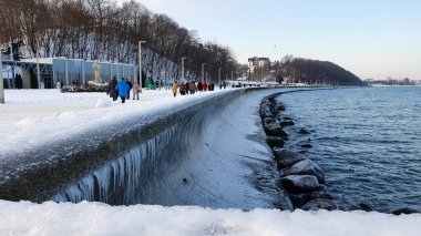 Gdynia, Polonya - 17 Ocak 2021: kış yürüyüşü. Polonya 'nın Gdynia kentindeki Baltık deniz bulvarında yürüyen insanlar. Gdynia, Polonya 'da Baltık Denizi' nin önemli bir limanıdır..
