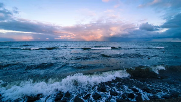 Dalgalı deniz ve batan güneşin renklerinde gökyüzü