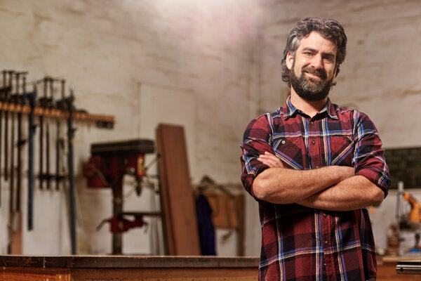 craftsman standing in workshop with arms folded