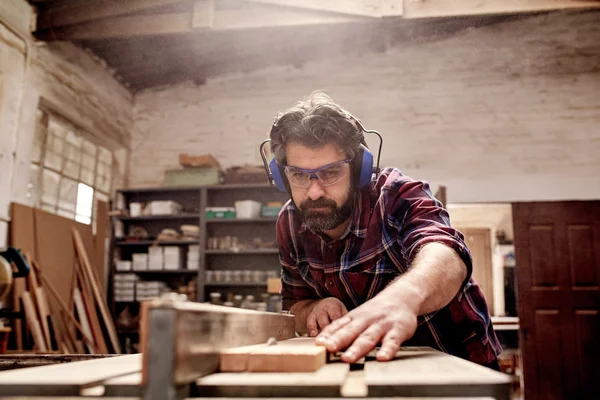Tischler schneidet Stück Holz in Werkstatt — Stockfoto