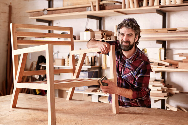 artisan carefully sanding chair frame
