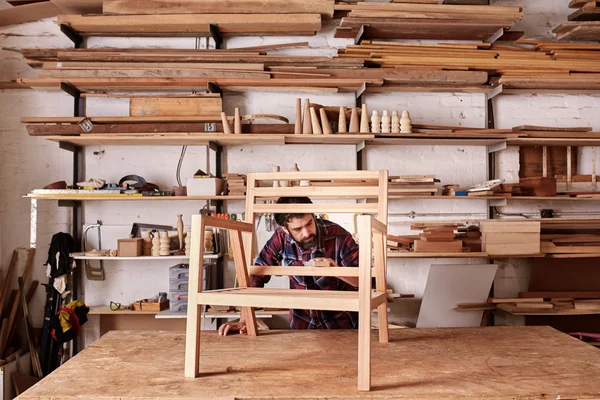 Artisan carefully sanding chair frame — Stock Photo, Image