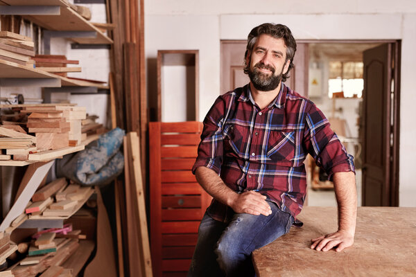 craftsman sitting in woodwork studio for portrait