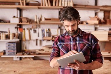 ahşap atölyesinde tablet üzerinde çalışan usta