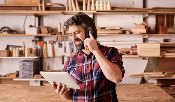 Carpenter using mobile and holding tablet — Stock Photo, Image