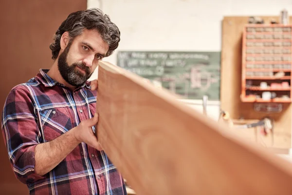 Craftsman looking down length of plank — Stock Photo, Image