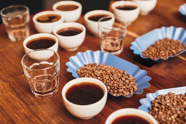 Variedad de café en tazas y frijoles en la mesa — Foto de Stock