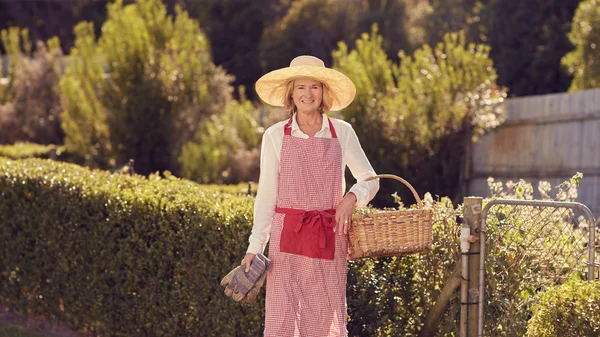 Woman holding basket and gardening gloves — Stockfoto