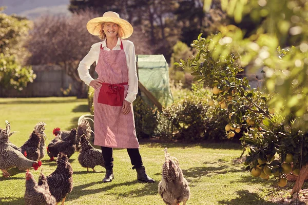 Femme âgée dans la cour arrière avec des poulets — Photo