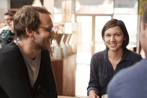 Frau sitzt mit Freunden in modernem Café — Stockfoto