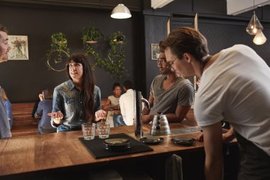 Woman chatting with colleagues at wooden counter