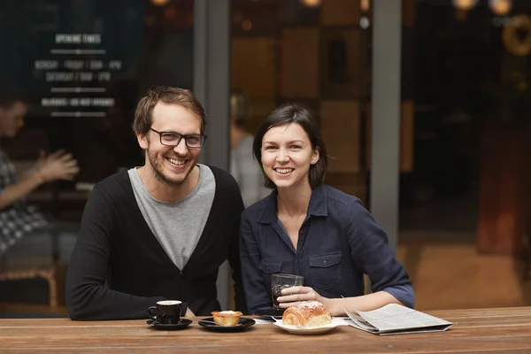 Пара улыбается в камеру наслаждаясь кофе — стоковое фото