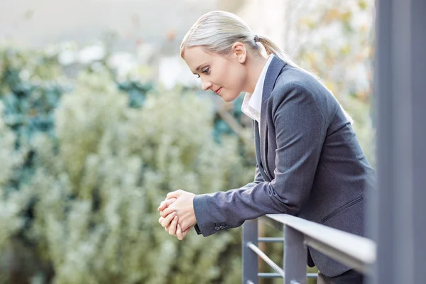 Businesswoman leaning against railing of balcony — Stock Photo, Image