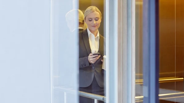 Empresária mensagens de texto alguém no elevador — Fotografia de Stock