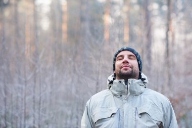 man breathing deeply in winter forest clipart