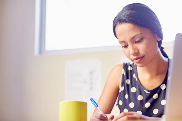 Vrouw schrijven zittend in office — Stockfoto