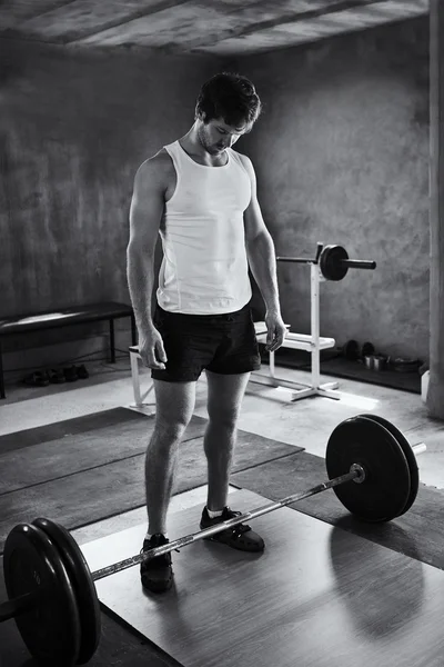 Starker Mann schaut auf Gewichte zum Heben — Stockfoto