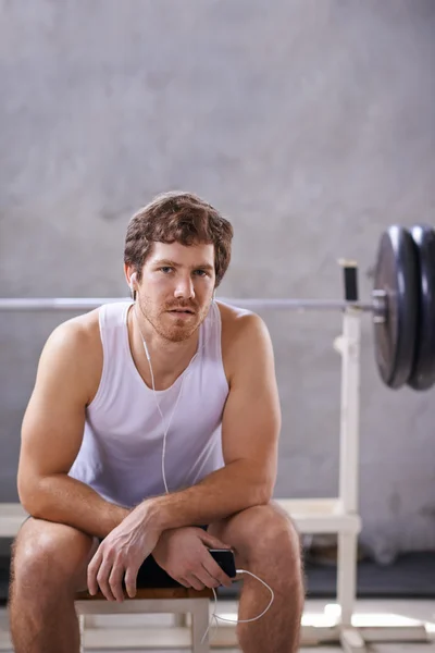 Człowiek z słuchawki siedzi prywatną siłownię — Zdjęcie stockowe