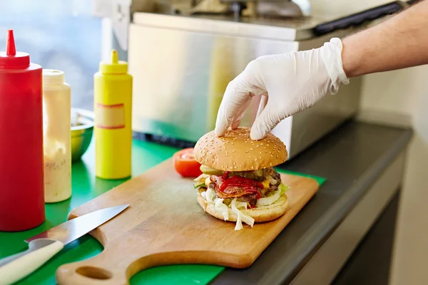 Mano poner panecillo superior en hamburguesa — Foto de Stock