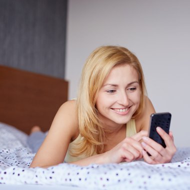 yatakta cep telefonu kullanan kadın