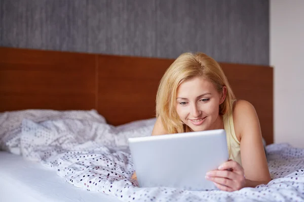 Женщина работает на планшете в постели — стоковое фото