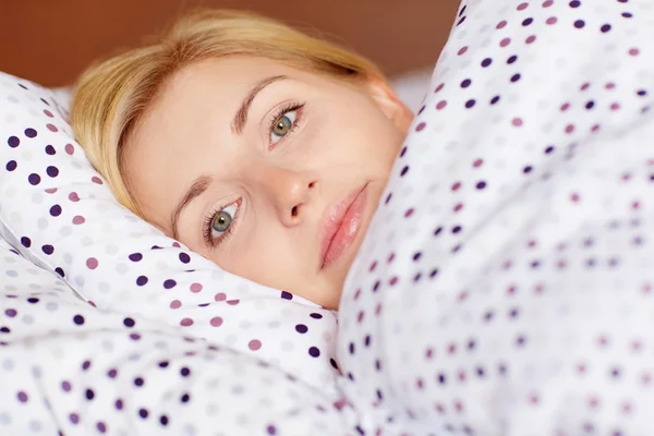 Kvinne som ligger våken i sengen – stockfoto