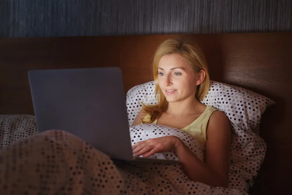 Yatakta dizüstü bilgisayarda çalışan kadın. — Stok fotoğraf