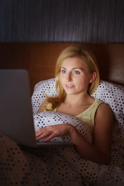 Женщина работает на ноутбуке в постели — стоковое фото