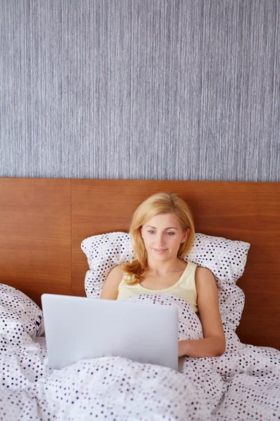 Kobieta pracująca na laptopie w łóżku — Zdjęcie stockowe
