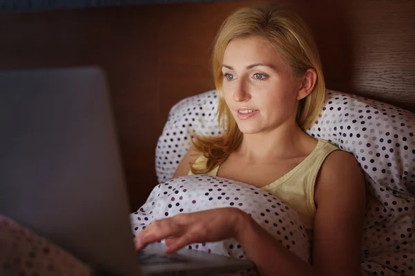 Kobieta pracująca na laptopie w łóżku — Zdjęcie stockowe