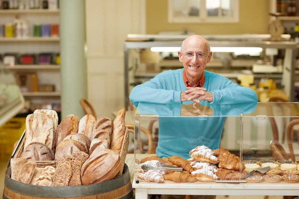 Proprietário deli em pé na exibição de pastelaria — Fotografia de Stock