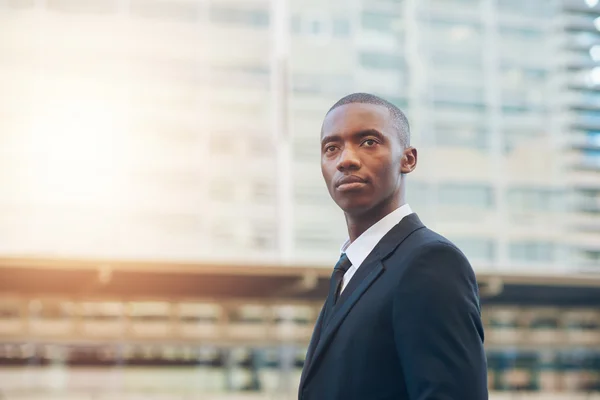 Businessman looking serious in city with sunflare — Stock Photo, Image