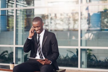 telefon ve tablet kullanırken gülüyor işadamı