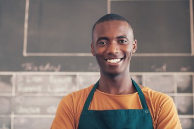 Afrikalı zanaatkar atölyede ayakta ve gülümseyerek