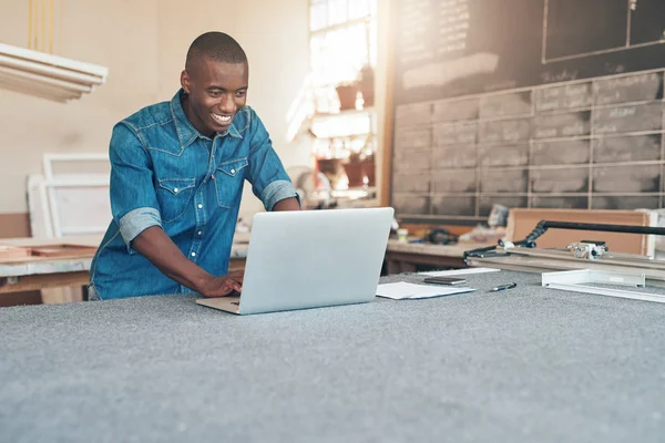 Business owner using laptop in workshop — Stock Photo, Image