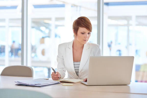 Affärskvinna sitter vid skrivbordet i lit kontor — Stockfoto
