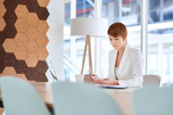 Mujer de negocios en la sala de juntas leyendo el mensaje por teléfono — Foto de Stock