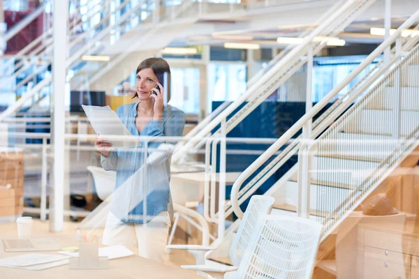 Mujer de negocios leyendo informe mientras habla por teléfono — Foto de Stock