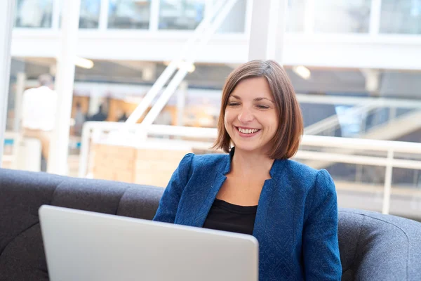 Zakenvrouw glimlachend tijdens het gebruik van laptop op de Bank — Stockfoto